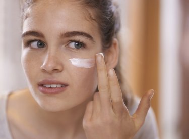 Teenage girl applying moisturizer